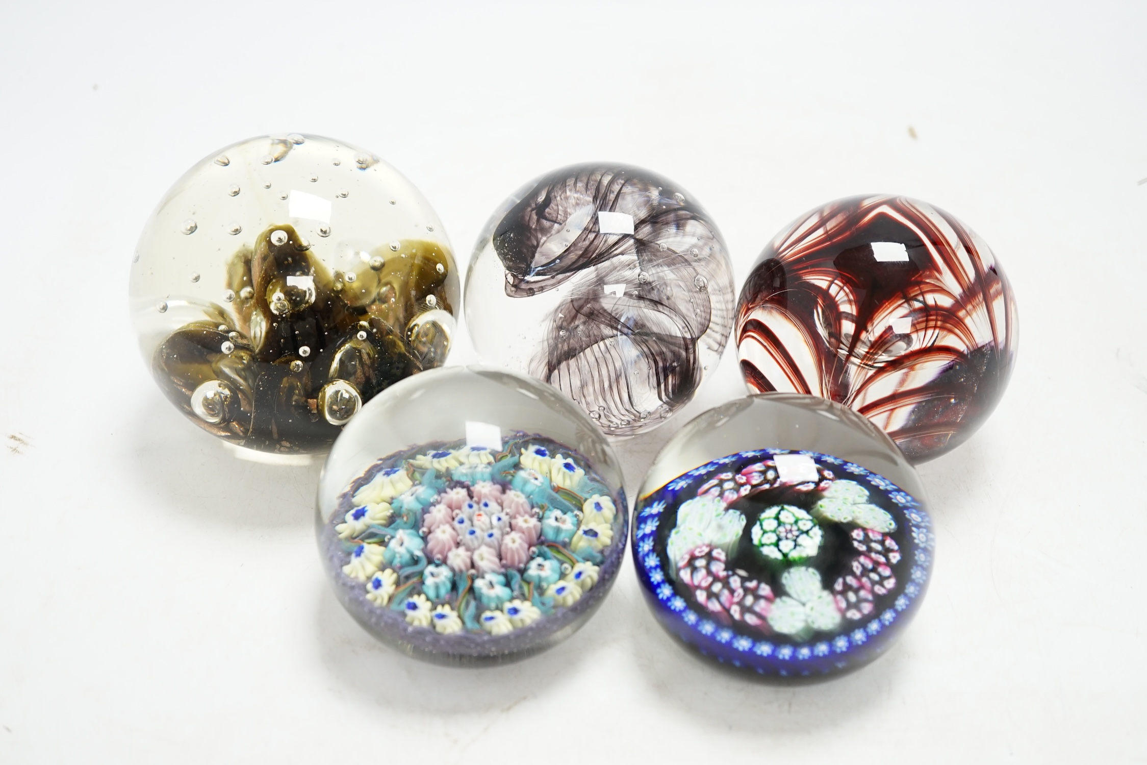 Five glass paperweights to include a Langham Glass House example and two millefiori examples, largest 9cm diameter., Condition - four good, one with impact damage